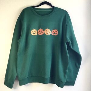 Forest green soft sweater with four pumpkins with carved faces print Halloween